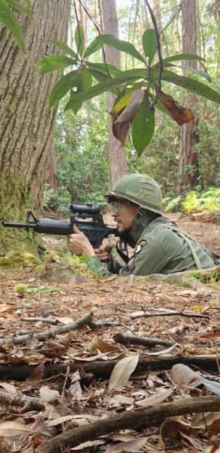 Airsoft player taking cover in woodland